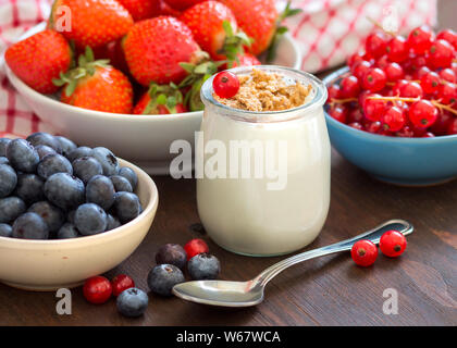 Glas mit frischem Joghurt, Früchten und Müsli auf Holz in der Lage Stockfoto