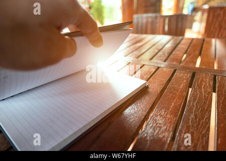 Hand öffnen Notebook auf Holztisch, Sonnenlicht Wirkung Stockfoto