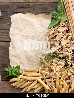 Pasta, Kräuter und Papier auf Holz- Hintergrund Stockfoto