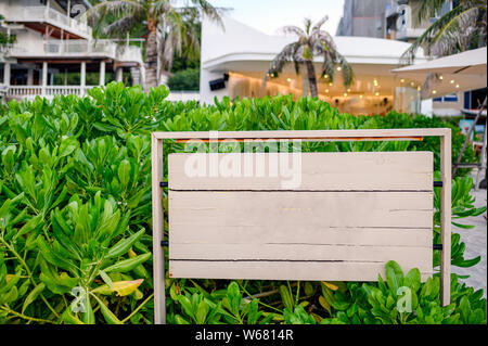 Holz- Schild mit grünen Anlage am Strand Stockfoto
