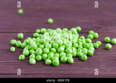 Junge grüne Erbsen auf einem hölzernen Hintergrund verstreut Stockfoto