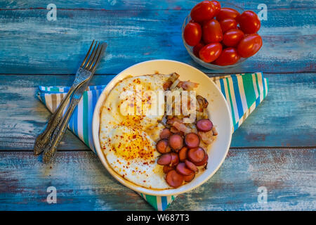 Rührei mit Speck, Zwiebeln und Würstchen. Auf einem Teller auf den Tisch. Stockfoto