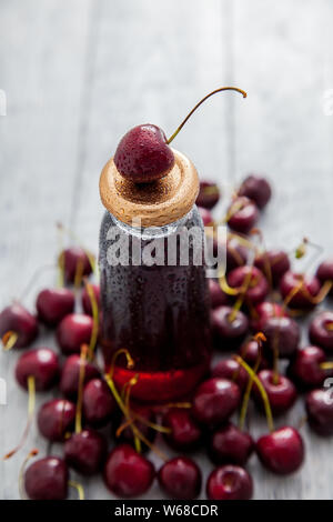 Cherry drink Flasche mit frischen Kirschen Beeren auf Holz- Hintergrund. Ansicht von oben. Stockfoto