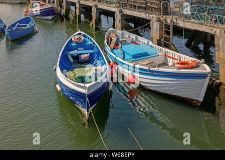 Whitby. Die Boote sind in der Nähe von einem Holzsteg mit Hummer Töpfe gestapelt. Zwei bunte Jollen sind im Wasser wider. Stockfoto