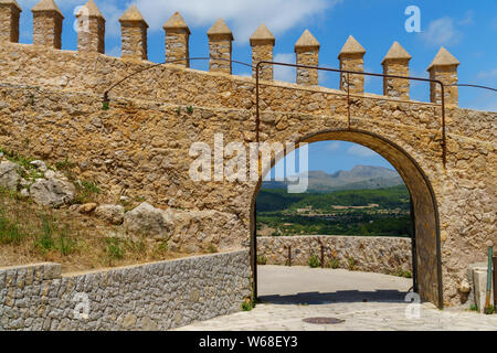 Gatter öffnen in eine Mauer ermöglicht einen schönen Blick auf einen weit entfernten Landschaft verstreute Häuser in einem Wald, Berge und blauer Himmel mit Wolken Stockfoto