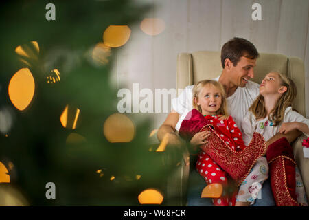 Vater und seine beiden Töchter mit ihren Strümpfe am Weihnachtstag. Stockfoto