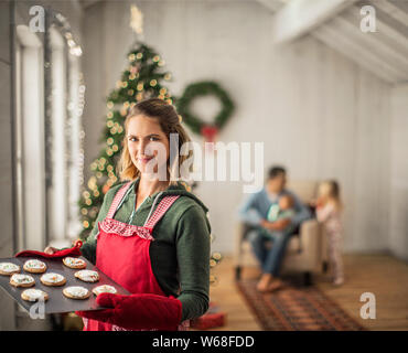Porträt eines lächelnden Frau mit einem Fach der frisch gebackene Weihnachtsplätzchen. Stockfoto