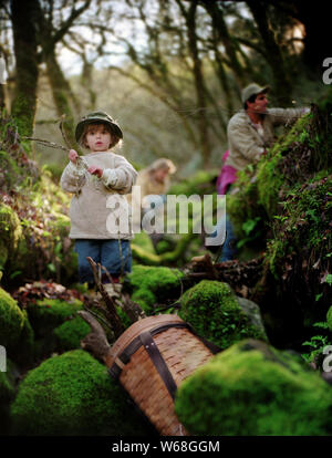 Vorderansicht eines kleinen Jungen auf einem bemoosten Felsen. Stockfoto