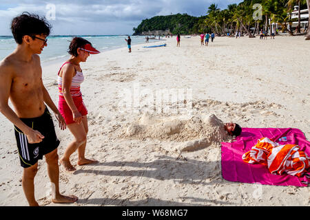 Touristen werden in Sand, White Beach, Boracay, Aklan Provinz der Philippinen. Stockfoto