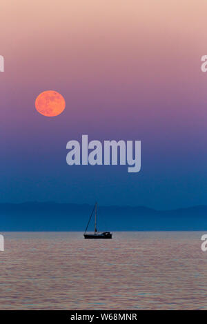 Seltene rote Mond über das Mittelmeer in Spanien mit einem Fisherman's Boot am Horizont Stockfoto