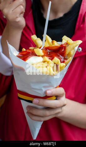 Essen der Belgischen Bratkartoffeln Pommes mit Ketchup und Mayonnaise, Straße fast food, ungesunde Nahrung Stockfoto