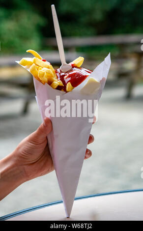 Essen der Belgischen Bratkartoffeln Pommes mit Ketchup und Mayonnaise, Straße fast food, ungesunde Nahrung Stockfoto