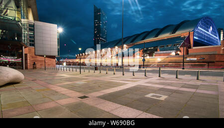 Lange Belichtung bei Nacht der Straßenbahn, die in der Lower Mosley Street mit Manchester Central, Bridgewater Hall und Beetham Tower im Hintergrund Stockfoto