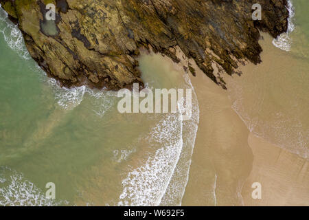 Von oben nach unten Luftbild von Wellen gegen felsigen und sandigen tropischen Strand brechen Stockfoto