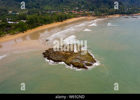 Antenne drone Ansicht einer kleinen Leuchtturm auf einer felsigen Insel direkt an einem Sandstrand und rauer See Stockfoto