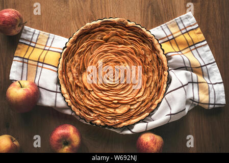 Apfelkuchen dekoriert in Form einer Blume, in einem Fach, auf Küchenpapier, Äpfel Früchte umgeben, auf vintage Tabelle. Oben Blick auf tatsy Apple p Stockfoto