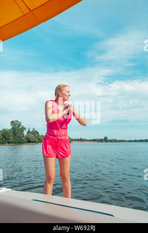 Lächelnde blonde Langhaarige junge Frau in nassen Kleidern Stockfoto
