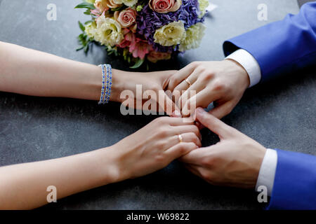 In der Nähe der Hochzeit Hände mit Ringen und einem Blumenstrauß auf dem Tisch liegen Stockfoto