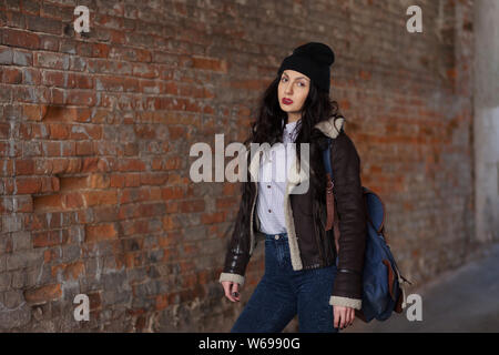 Outdoor Lifestyle Portrait von hübschen jungen Mädchen, tragen hipster Swag grunge Style auf der städtischen Hintergrund. Tragen Hut und Jeans mit Rucksack. Feder fa Stockfoto