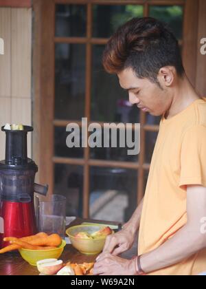 14. April 2019 - Kediri, Indonesien : ein junger indonesischer Mann, der Saft mit einem langsamen Entsafter zubereitete. Stockfoto