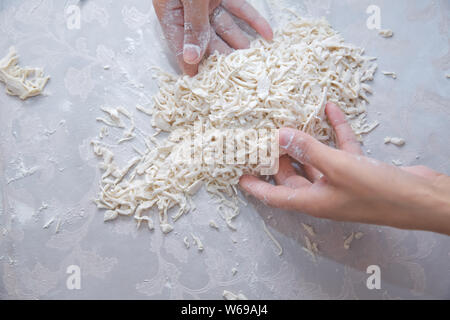 Junge Haus Frau Vorbereiten der hausgemachte Pasta in der Küche. Teig schneiden lange Streifen für Kochen Pasta. Hausgemachte Speisen Vorbereitung Konzept. Nahaufnahme des p Stockfoto