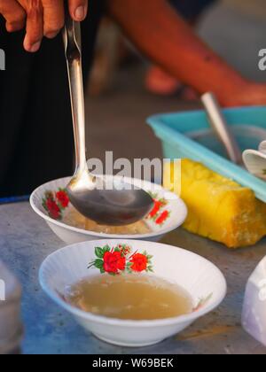 Verkäufer bereit tahok für Kunden. Tahok ist ein Pudding - wie Teller mit einem unverwechselbaren süßen Geschmack der javanischen Zucker. Stockfoto