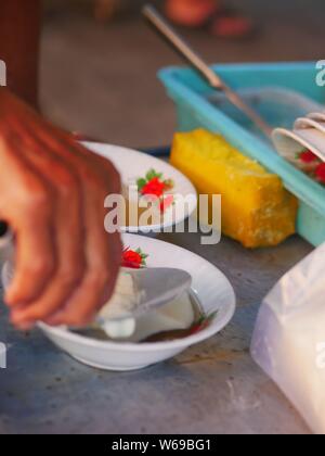 Verkäufer bereit tahok für Kunden. Tahok ist ein Pudding - wie Teller mit einem unverwechselbaren süßen Geschmack der javanischen Zucker. Stockfoto