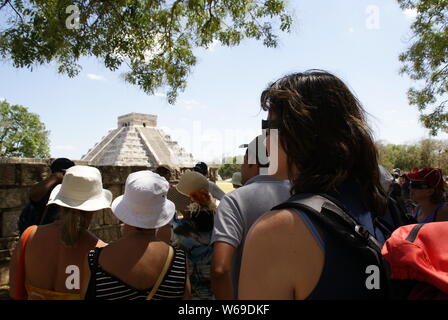 Yucatan, Mexiko - 19. März 2010: Gruppe von Touristen nehmen Zuflucht vor der Sonne und der Tempel der Sonne in Chichen Itza betrachten. Stockfoto