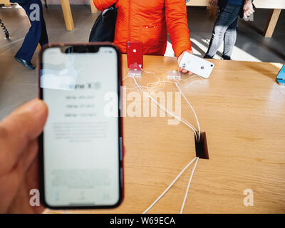 Paris, Frankreich, 26.Oktober 2018: Defokussierten Sicht des Menschen Hand neueste red iPhone XR Smartphone während am Tag der Markteinführung von Apple Computern mit Frau bewundern weiß Telefon Hintergrund hergestellt Stockfoto