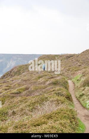 Wanderer Wandern auf dem South West Coastal Path zu Hl. Agnes auf einem dunstigen Frühling durch die Heide. North Cornwall, UK. Stockfoto