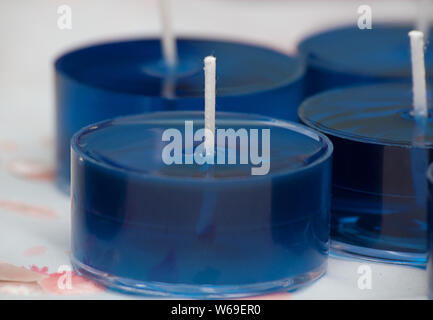 Kerzen, Teelichter, diese kleinen blauen Teelicht Kerzen sind in flüssiger Form auf ein kerzenmacher Bank. Weiß Dochte werden in das flüssige Wachs Cups. Stockfoto