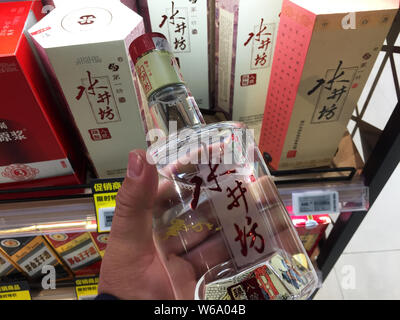 ---- Ein Kunde Geschäfte für eine Flasche Schnaps Shuijingfang in einem Geschäft in Shanghai, China, 1. Dezember 2017. Shuijingfang, einem großen chinesischen baijiu Stockfoto