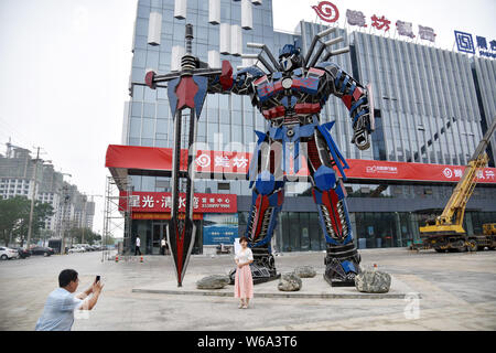 Lokale chinesische Bewohner nehmen Sie Bilder vor eine Replik von Optimus Prime aus der Automobil Botschaften vor einem kommerziellen Komplex in Liaocheng ci gemacht Stockfoto