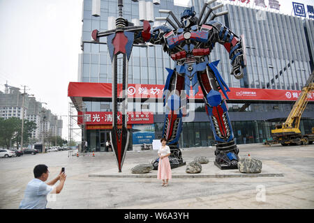 Lokale chinesische Bewohner nehmen Sie Bilder vor eine Replik von Optimus Prime aus der Automobil Botschaften vor einem kommerziellen Komplex in Liaocheng ci gemacht Stockfoto