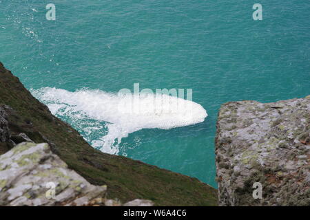 Patch von Gischt Meer Schaum auf eine ruhige türkisfarbene Meer von St Agnes Head, North Cornwall. Marine, UK. Stockfoto