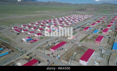 Luftbild der Neuen Residenz der Kasachen in die roten Dächer aufgereiht auf einer Wiese in Yiwu County, Hami Stadt im Nordwesten Chinas Xinjiang Uyghur Autonomou Stockfoto