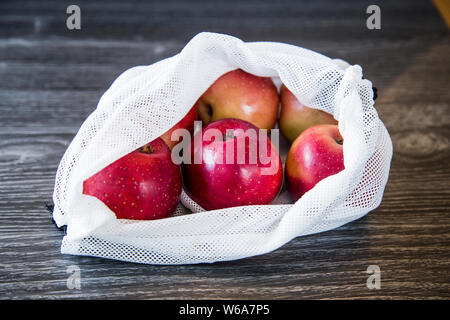 NZ rote Äpfel aus dem Supermarkt in wiederverwendbaren Taschen produzieren von upcycling Alte single use Plastiktüten gekauft. Gibt neues Leben aus Kunststoff Stockfoto