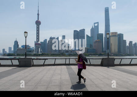Ein Tourist schützt sich mit einem Regenschirm aus der sengenden Sonne, wie sie der Bund in Shanghai, China, 26. Juni 2018 Besuche. Shanghai wetter Präsidium i Stockfoto