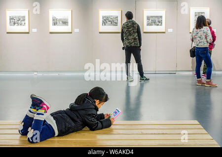 ---- Eine junge chinesische Mädchen spielt ein Spiel auf einem Smartphone während einer Fotografie Ausstellung in Dalian im Nordosten der chinesischen Provinz Liaoning, Stockfoto