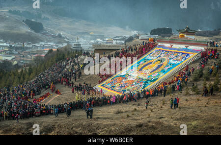 ---- Lamas und Anwohner Blick auf eine riesige Thangka Buddha am Langmu Tempel während der Sho Dun Festival, gemeinhin als Joghurt Fest bekannt Stockfoto