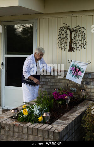 Eine ältere Frau überprüft Ihr Blume Garten vor ihrem Haus in Warren, Indiana, USA. Stockfoto