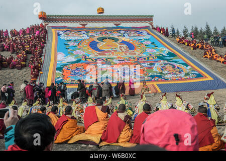 ---- Lamas und Anwohner Blick auf eine riesige Thangka Buddha am Langmu Tempel während der Sho Dun Festival, gemeinhin als Joghurt Fest bekannt Stockfoto