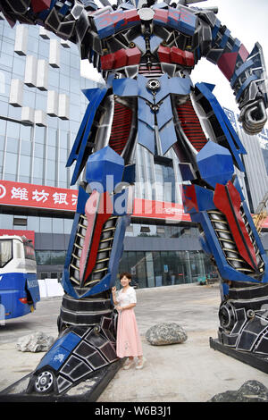 Eine chinesische Frau Posen für Fotos mit einer Replik von Optimus Prime aus der Automobil Botschaften vor einem kommerziellen Komplex in Liaocheng City gemacht, Eas Stockfoto