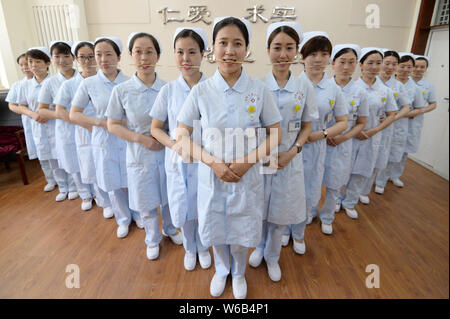 Weibliche Krankenschwestern biss Stäbchen lächelnd für Patienten, die an der Praxis der Welt Lächeln Tag in einem Krankenhaus in Handan Stadt zu markieren, der Norden der Provinz Hebei, China Stockfoto