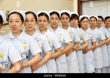 Weibliche Krankenschwestern biss Stäbchen lächelnd für Patienten, die an der Praxis der Welt Lächeln Tag in einem Krankenhaus in Handan Stadt zu markieren, der Norden der Provinz Hebei, China Stockfoto