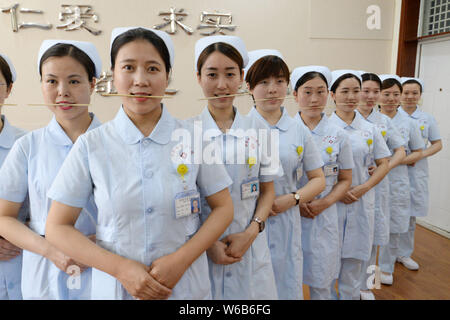 Weibliche Krankenschwestern biss Stäbchen lächelnd für Patienten, die an der Praxis der Welt Lächeln Tag in einem Krankenhaus in Handan Stadt zu markieren, der Norden der Provinz Hebei, China Stockfoto