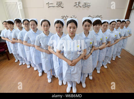 Weibliche Krankenschwestern biss Stäbchen lächelnd für Patienten, die an der Praxis der Welt Lächeln Tag in einem Krankenhaus in Handan Stadt zu markieren, der Norden der Provinz Hebei, China Stockfoto