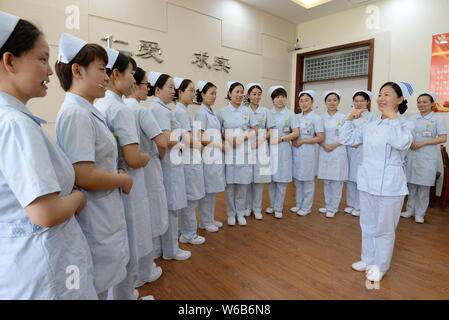 Weibliche Krankenschwestern biss Stäbchen lächelnd für Patienten, die an der Praxis der Welt Lächeln Tag in einem Krankenhaus in Handan Stadt zu markieren, der Norden der Provinz Hebei, China Stockfoto