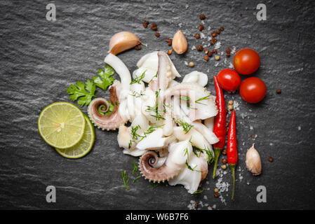 Tintenfisch Salat mit Zitrone Kräuter und Gewürze auf dunklem Hintergrund Top View/Tentakeln Krake warme Vorspeise essen heiß und würzig Chili Sauce seafood Cooke Stockfoto