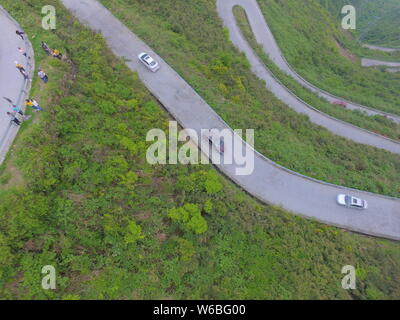 Autos fahren auf einem Abschnitt der kurvenreiche Straße mit 45 Kurven Verknüpfung Xiushan Tujia, Miao autonomen Grafschaft und Chuanhegai malerischen Ort von Nebel umgeben Stockfoto